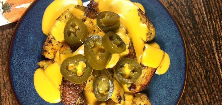 spiced potato wedges with vegan nacho cheese and spicy jalapeño slices